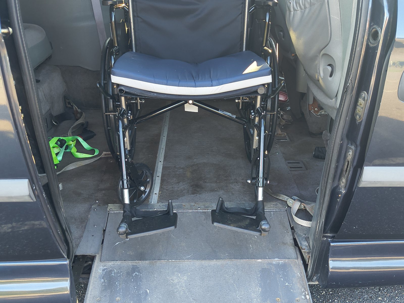 A wheelchair positioned on the vehicle's ramp, ready to load